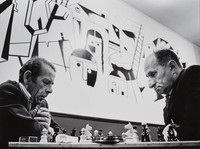 Chess players at the Jewish Club in Lodz.  At the outbreak of WW II, one-third of the city (230,000) were Jewish.  Now (1975) approximately 500 are left. Some gathering here to socialize, watch television, play cards...  The mural, done in 1960, by Adam (Aron)  Muszka, depicts the Holocaust.