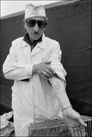 Robin Dawidowicz, displaying his arm tatooed in Mauthausen concentration camp. Behind his doughnut stand at Lublin's outdoor market. 1975