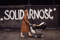 Woman walking with a baby carriage on a street with Solidarnosc signage, Gdansk, Poland, December 1980