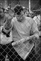 Man looking at faces of those killed on 911 in that days' New York Times at the first anniversary of the attack at the World Trade Center at Ground Zero, NY, NY, Sept. 11, 2002
